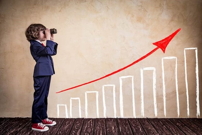 Child with binoculars watching a graph of growing columns, symbolizing business growth and the vision needed to nurture a closely-held business.