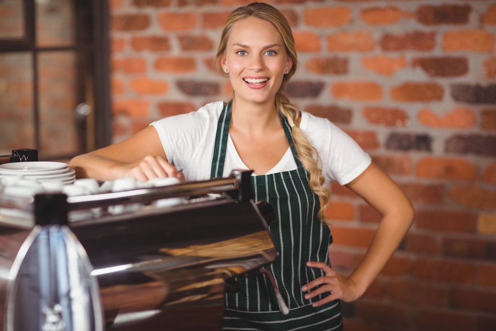 Portrait of a pretty barista with hands on hips at the coffee shop