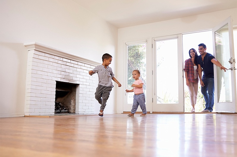 family of four smiling entering empty household