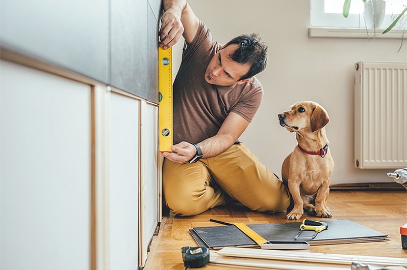 man using measuring tools next to dog