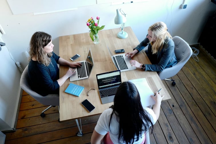 Confident woman entrepreneur in a bright office, working on a laptop and reviewing business documents, symbolizing success and growth in small business ownership.